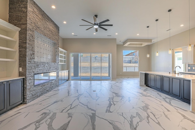 kitchen featuring sink, hanging light fixtures, ceiling fan, built in features, and a fireplace