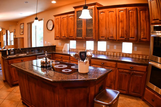 kitchen with a center island, sink, kitchen peninsula, pendant lighting, and black electric stovetop