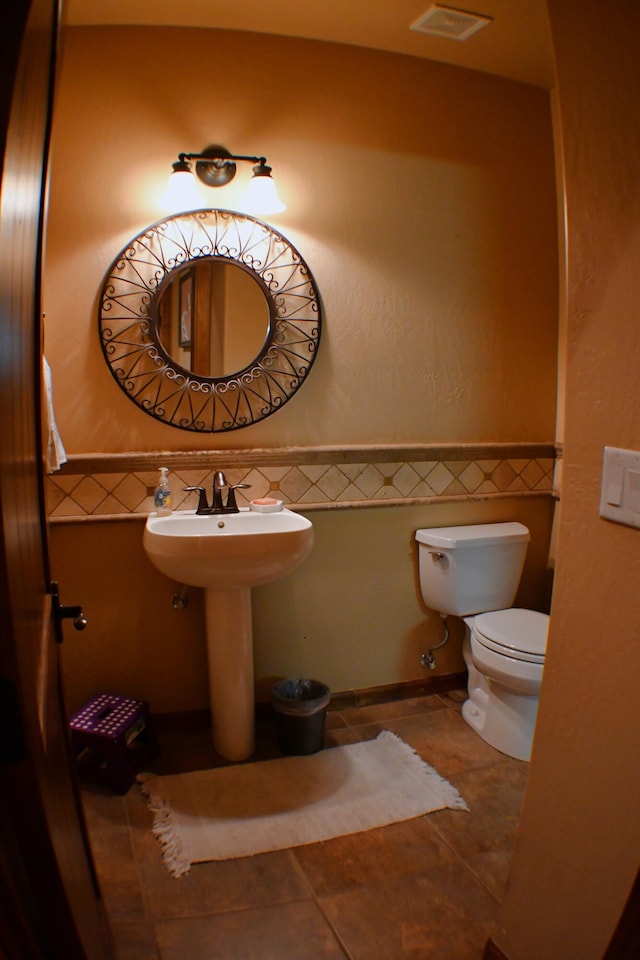 bathroom featuring tile patterned flooring, toilet, and tile walls