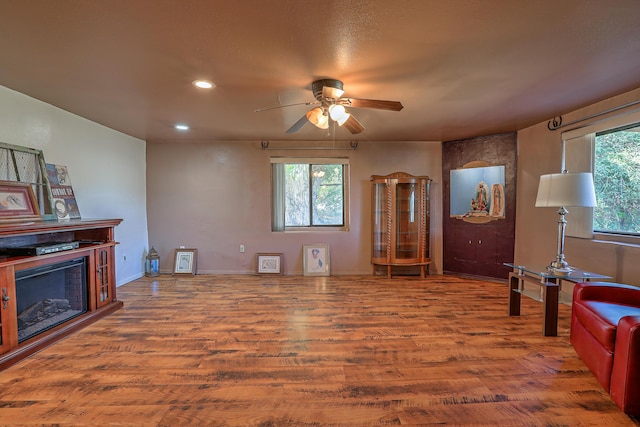 living room with a fireplace, wood-type flooring, and ceiling fan