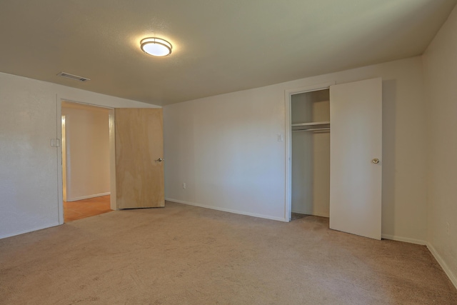 unfurnished bedroom featuring light carpet and a closet