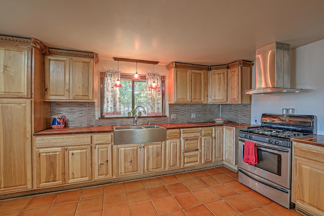 kitchen featuring pendant lighting, wall chimney exhaust hood, sink, light tile patterned floors, and stainless steel gas range