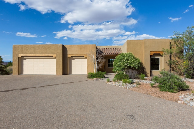 pueblo revival-style home featuring a garage