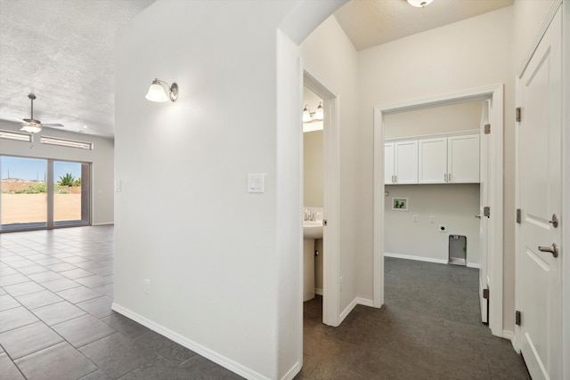 hall featuring a textured ceiling and dark tile patterned flooring