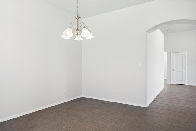 spare room with vaulted ceiling and an inviting chandelier