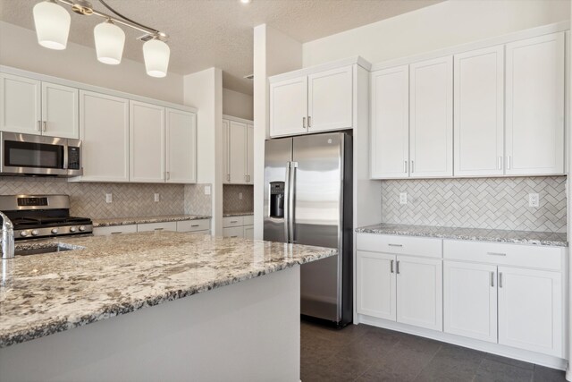 kitchen with white cabinetry, stainless steel appliances, a textured ceiling, decorative light fixtures, and decorative backsplash