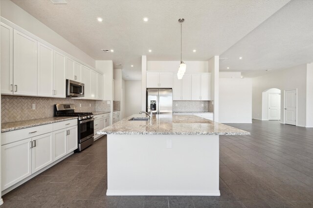 kitchen with a kitchen island with sink, white cabinets, and appliances with stainless steel finishes