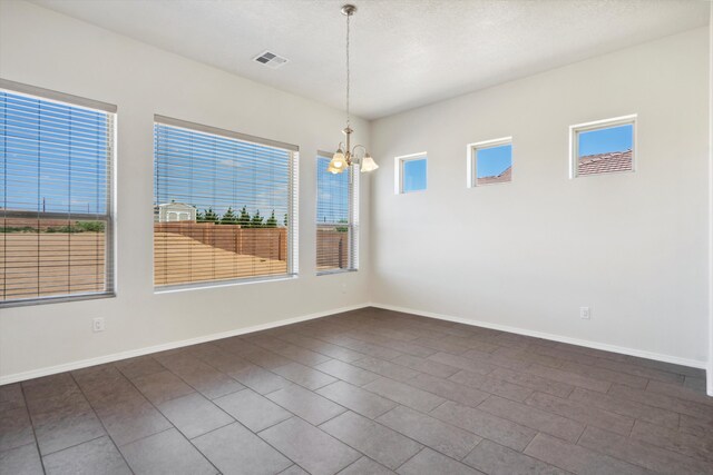 unfurnished dining area with a chandelier, a textured ceiling, and a wealth of natural light