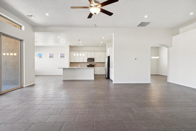 unfurnished living room with dark tile patterned floors, ceiling fan with notable chandelier, and a textured ceiling