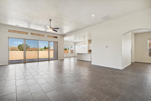 unfurnished living room featuring tile patterned flooring, ceiling fan, and a textured ceiling