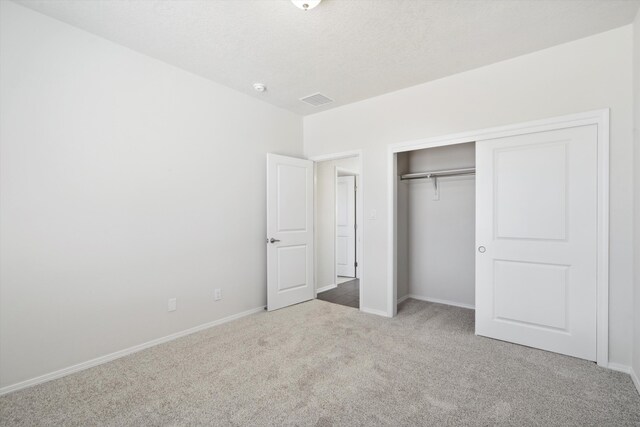 unfurnished bedroom featuring light colored carpet and a closet