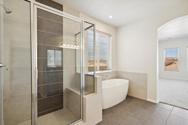 bathroom featuring plus walk in shower, tile patterned floors, and a wealth of natural light