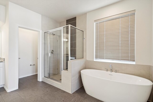 bathroom with tile patterned flooring, vanity, shower with separate bathtub, and a textured ceiling