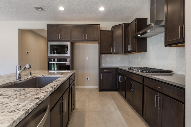 kitchen featuring light stone countertops, sink, wall chimney exhaust hood, light tile patterned floors, and appliances with stainless steel finishes