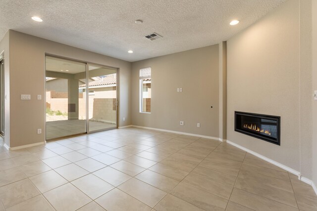 tiled empty room with a textured ceiling