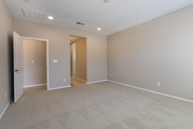 unfurnished room featuring a textured ceiling and light colored carpet