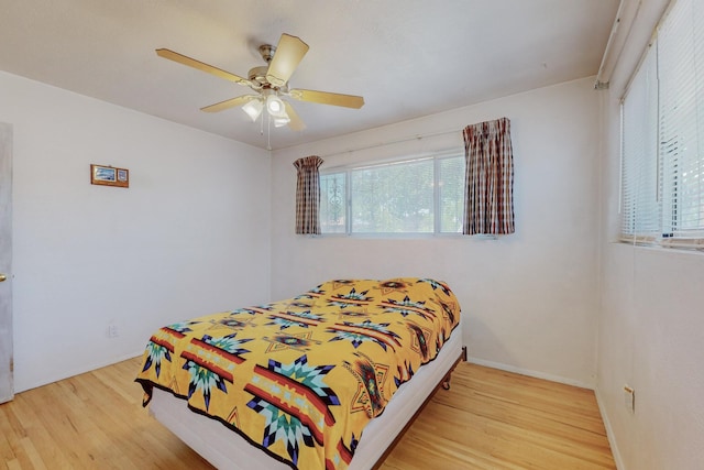 bedroom with light wood finished floors, ceiling fan, and baseboards