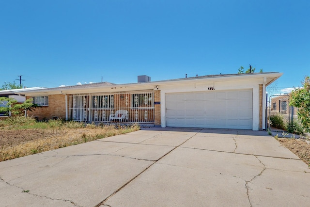 ranch-style home featuring a garage, concrete driveway, brick siding, and central AC