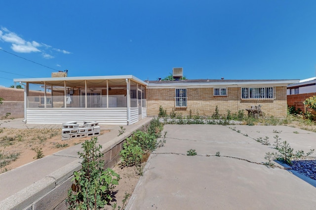 view of front facade with a sunroom, brick siding, a patio, and fence