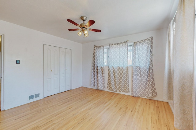 unfurnished bedroom featuring light wood-style floors, a closet, visible vents, and ceiling fan