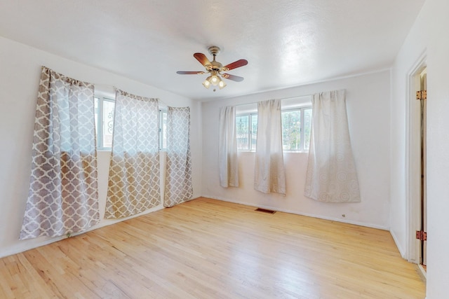 spare room with light wood-style floors, visible vents, and a ceiling fan