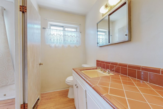 full bathroom with walk in shower, vanity, toilet, and wood finished floors