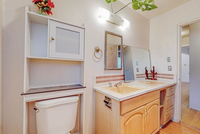 bathroom with tasteful backsplash, wood-type flooring, vanity, and toilet