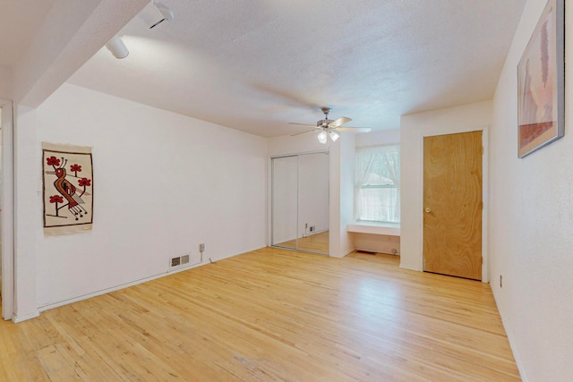 unfurnished room featuring a textured ceiling, light wood-type flooring, and ceiling fan