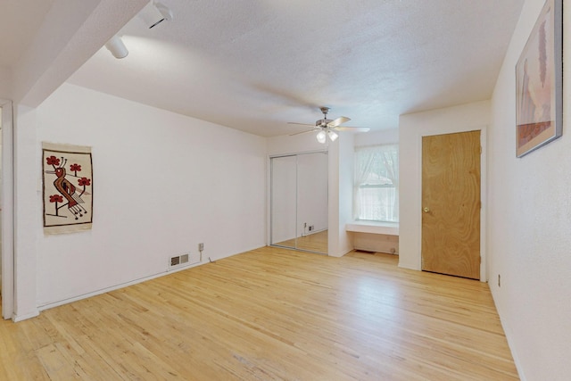 interior space featuring light wood-type flooring, visible vents, ceiling fan, and a textured ceiling