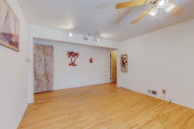 spare room with rail lighting, light wood-type flooring, and ceiling fan