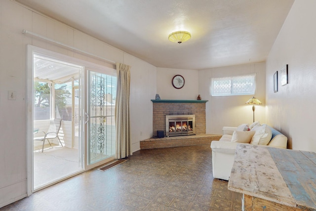 living room featuring dark floors, a brick fireplace, and visible vents