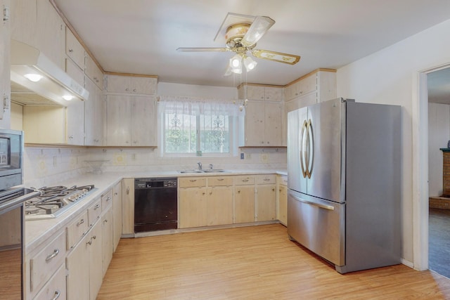 kitchen featuring stainless steel appliances, light countertops, a sink, and light wood finished floors