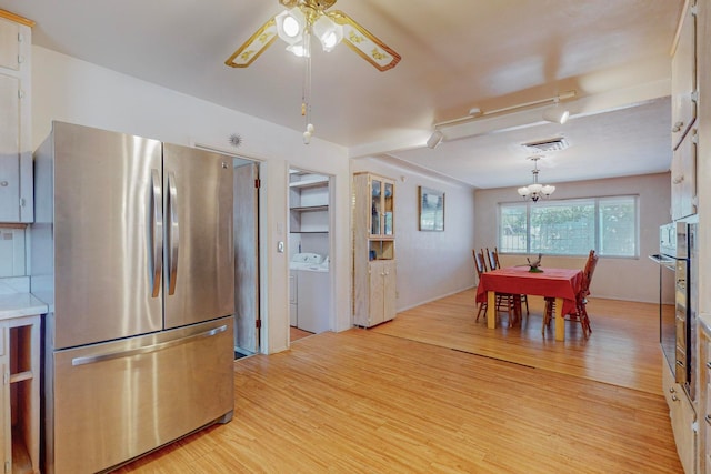 interior space featuring decorative light fixtures, light hardwood / wood-style floors, stainless steel refrigerator, and washer / clothes dryer