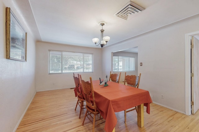 dining space featuring a chandelier, light wood-type flooring, visible vents, and baseboards