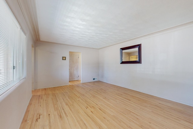 unfurnished room with light wood-type flooring, visible vents, and crown molding