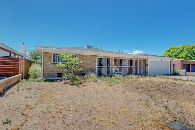 back of property featuring a garage and brick siding