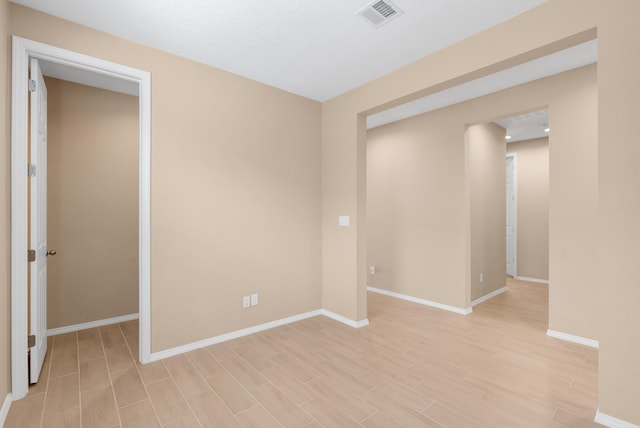 empty room with visible vents, baseboards, and light wood finished floors