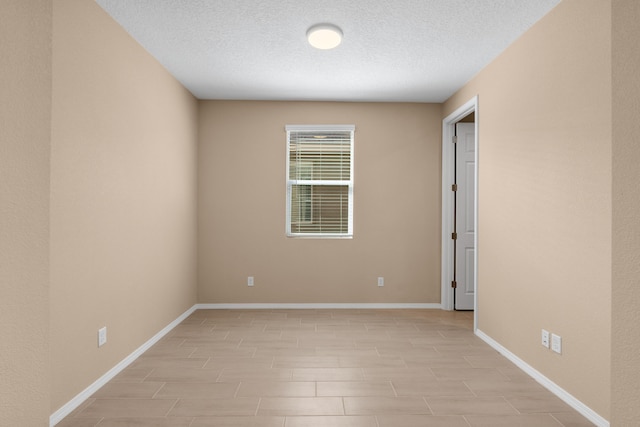 empty room featuring baseboards and a textured ceiling