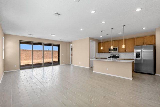 kitchen featuring backsplash, open floor plan, light countertops, appliances with stainless steel finishes, and brown cabinetry