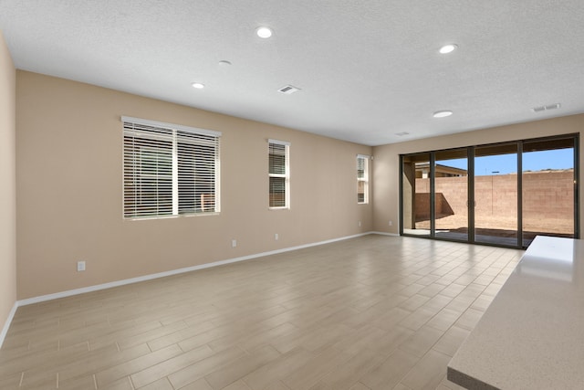 spare room featuring recessed lighting, baseboards, visible vents, and a textured ceiling