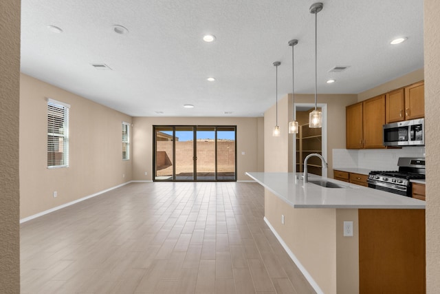 kitchen with backsplash, open floor plan, appliances with stainless steel finishes, brown cabinetry, and a sink