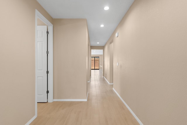 hall featuring light wood finished floors, recessed lighting, and baseboards