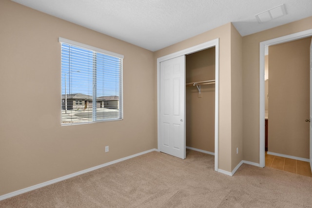 unfurnished bedroom with visible vents, baseboards, carpet floors, a closet, and a textured ceiling