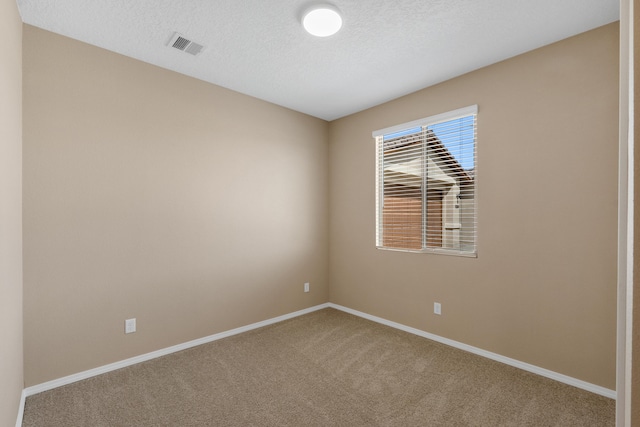 carpeted empty room with visible vents, a textured ceiling, and baseboards