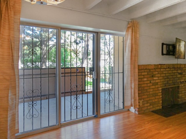 entryway featuring hardwood / wood-style flooring, a brick fireplace, and beam ceiling