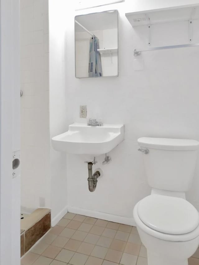 bathroom featuring sink, curtained shower, and toilet