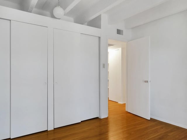 unfurnished bedroom with hardwood / wood-style flooring and multiple closets