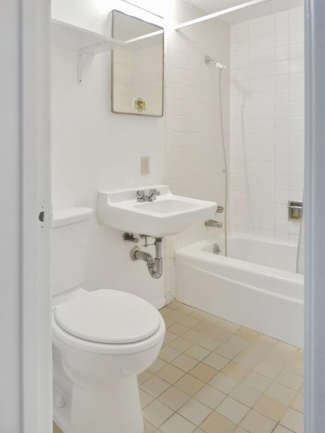 bathroom featuring tiled shower / bath combo, tile patterned floors, and toilet