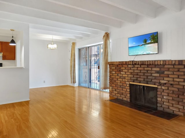 unfurnished living room featuring hardwood / wood-style floors, beam ceiling, and a fireplace