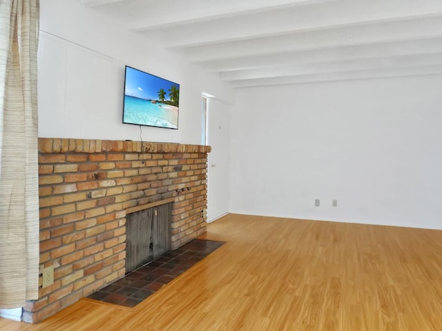 unfurnished living room with a brick fireplace, beam ceiling, and dark hardwood / wood-style floors